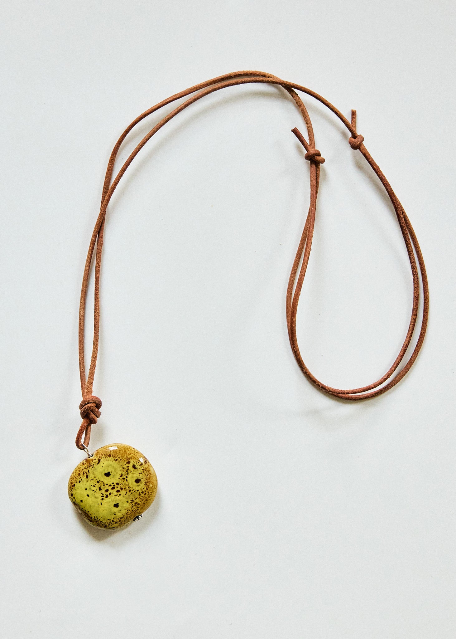 Chartreuse speckled ceramic pendant on adjustable brown leather cord necklace